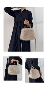 Detail view of cream faux fox fur shoulder bag with slender leather straps on model