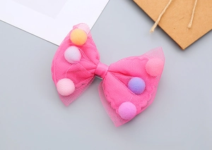 Detail of pink mesh bow hair clip with colorful mini pompoms for girls' hair styling
