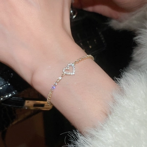 Elegant gold heart pendant bracelet with white zircon stones worn on wrist detail