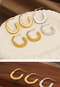 Detail showing gold and silver U-shaped stainless steel hoop earrings on a ceramic dish
