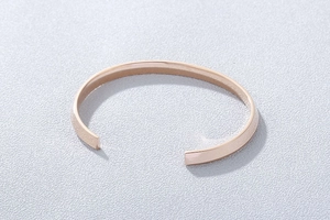 Detail view of the polished rose gold finish on a minimalist C-shaped open cuff bracelet