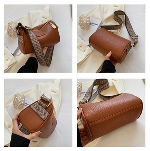 Detailansicht der braunen Ledertasche mit Litschi-Muster und breitem Jacquard-Gurtband