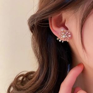 Elegant gold starburst stud earring with pearls worn by a model for a stylish look
