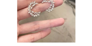 Detailed close-up of crescent wheat leaf silver earrings with sparkling zircon stones