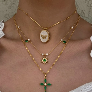 Gros plan d'un collier à médaillon doré vintage avec des pierres vertes