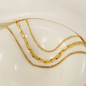 Detail of three-layer gold stainless steel necklace featuring various chain textures