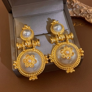 Macro detail of gold vintage palace earrings with pearl flower in velvet jewelry box