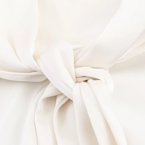 Vue macro du haut sans manches blanc crème avec détail de nœud en satin