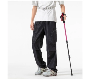 Detail of black tactical cargo pants showing multi-pocket design and matte texture
