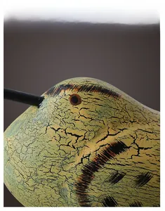 Close-up of the artistic crackle texture and hand-painted details on wooden bird decor