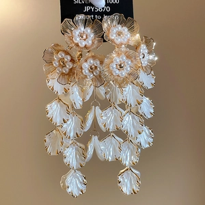 Macro view of vintage gold flower tassel earrings with pearls and white petals