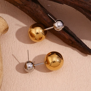 Makroaufnahme von zweifarbigen Gold- und Silber-Doppelperlenohrringen auf Holzgrund
