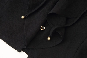 Detail of black textured fabric featuring decorative gold metallic bead embellishments