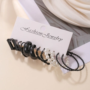 Detailed set of six pairs of black C-shaped hoop earrings and pearl studs on display card