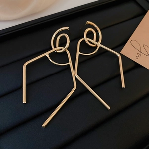 Detailed view of large gold geometric earrings with twisted loops in a jewelry box
