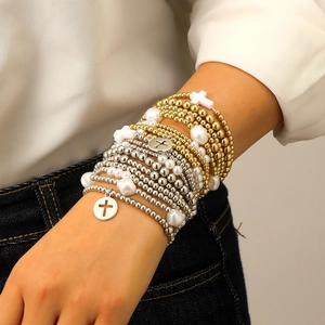 Dettaglio di bracciali elastici boho a strati con perle e ciondoli a croce