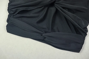 Detailed close-up of black dress featuring knot design and ruching texture on fabric