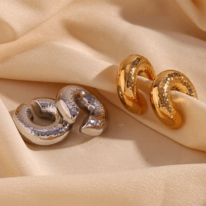 Detail of 30mm hammered texture gold and silver hoop earrings on satin fabric