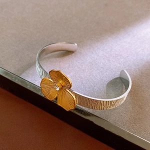 Detail of silver bangle featuring a gold textured flower with a sparkling crystal center