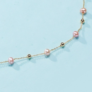 Macro detail of Edison pink pearls and gold beads on a minimalist necklace chain