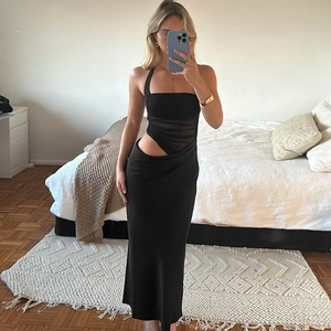 Détail d'une robe moulante noire avec patchwork en mesh et découpe asymétrique à la taille