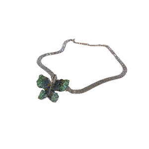 Minimalist green crystal butterfly necklace with bold woven metal chain on white background