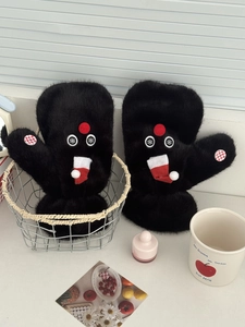 Detail of plush black mittens with cute monster eyes, red nose, and Christmas charms