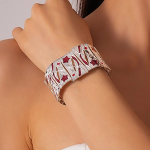 Macro detail of wide silver metal elastic bracelet featuring bold red star patterns