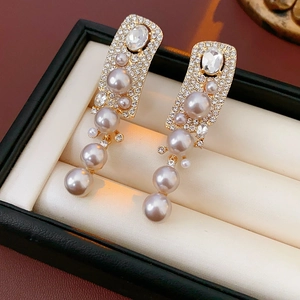 Detail of gold pearl drop earrings with rhinestones on a jewelry box liner