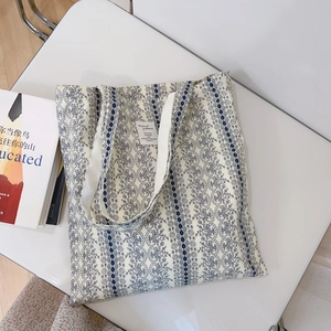 Detailed close-up of floral canvas tote bag with book on white surface for artistic lifestyle