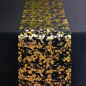 Detailed view of black polyester table runner with gold and green metallic foil pattern