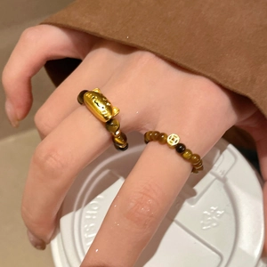 Detail of tiger eye bead rings with gold cat and coin charms worn by a model