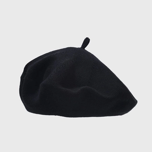 Close-up of black knitted beret top featuring a classic small stem design and fine texture