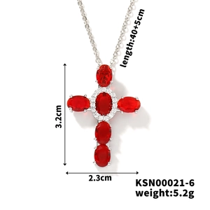 Detail view of silver cross necklace with red stones and measurements 3.2cm by 2.3cm