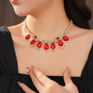 Detail of a vintage necklace with red teardrop crystals and ribbon bow design on a model