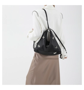 Detailed view of a black shoulder bag decorated with stylish silver metal bows