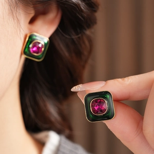 Detail of vintage square earrings with green enamel and rose red faceted gemstone