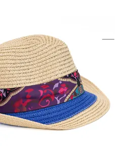 Detail of wide brim straw hat featuring purple geometric ribbon and blue woven edge