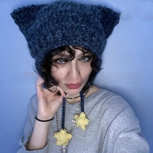 Detail of dark blue hand-knitted beanie with cat ears and yellow star hanging tassels