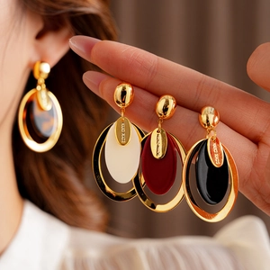 Detail showing handmade resin oval earrings in tortoiseshell, white, and wine red colors