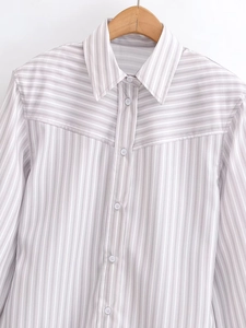 Detailed view of grey striped shirt fabric with white buttons and pointed collar