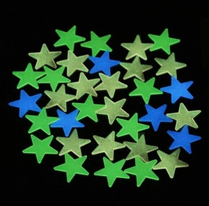 Detailed close-up of luminous star stickers in green and blue on a black background
