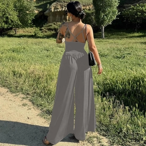 Back view of a grey backless wide-leg jumpsuit with delicate criss-cross straps in nature