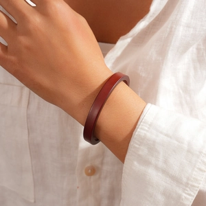 Detail of dark brown resin geometric bangle worn on wrist with white linen shirt
