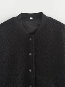 Detailed view of the black sherpa fleece texture and metallic snap buttons on jacket