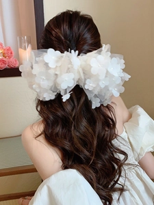 Detail of white 3D mesh flower hair clip with pearl beads on long brown wavy hair