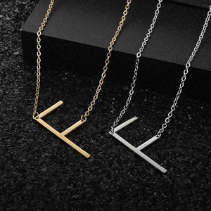 Macro detail of letter F pendants in gold and silver finish with cross chain