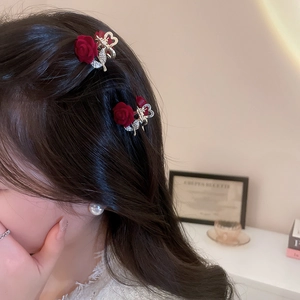 Detail of a mini red flocked rose hair claw with rhinestones on an elegant hairstyle