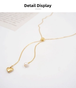 Detailed macro view of a gold heart pendant and pearl tassel on a Y-shaped necklace