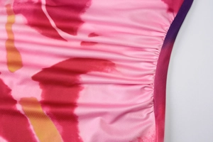 Macro detail of pink tie-dye fabric with elastic ruching and purple hem stitching